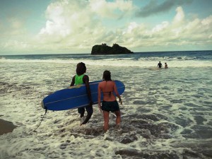 Surf instructor and student enter waves with board