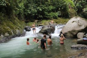People wading in a river with waterfalls