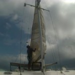 Man raising sail on sailboat