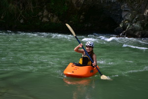 Happy girl in a orange kayak in a river