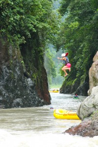 Rafter jumping from rock ledge into river